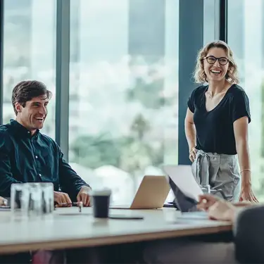 Laughing colleagues having a meeting in a conference room.