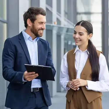 Two colleagues reviewing a tablet outside an office building.