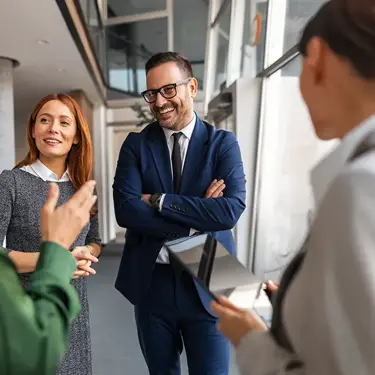 Four smiling colleagues discussing work together in an office.